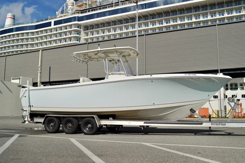 Slide: The Image of 2009 Sailfish 2860 CC boat on trailer, docked near a large cruise ship. - 2