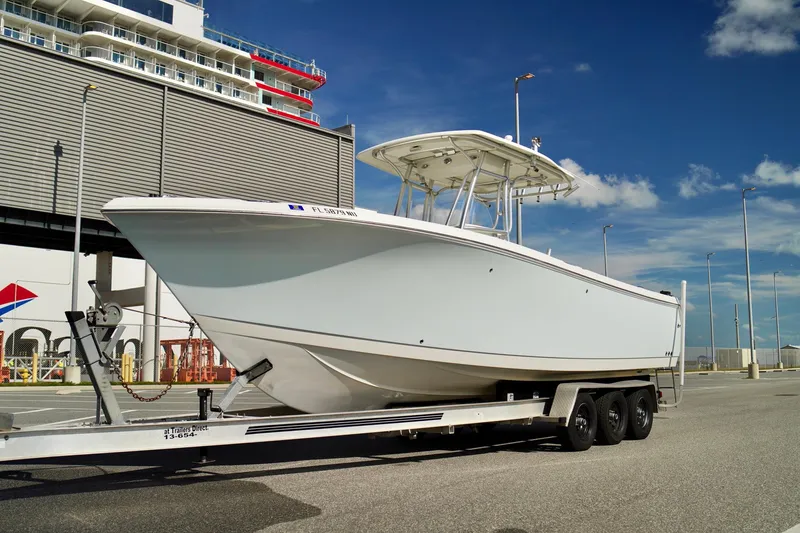 Slide: The Image of 2009 Sailfish 2860 CC boat on trailer, parked at a marina under clear blue skies. - 7