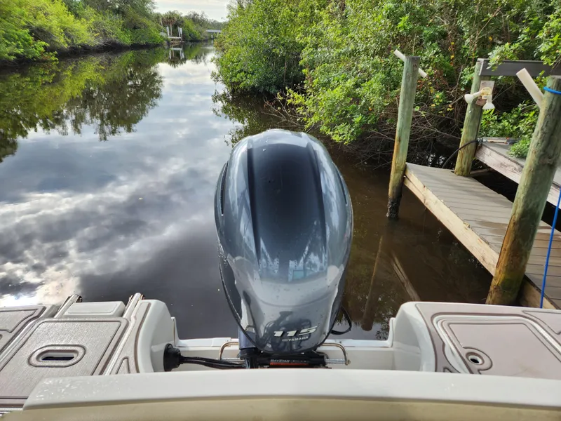 Slide: The Image of 2019 Hurricane SunDeck 187 OB boat on a calm river near a wooden dock. - 16