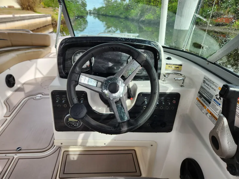 Slide: The Image of 2019 Hurricane SunDeck 187 OB boat steering wheel and dashboard, docked by a scenic waterway. - 20