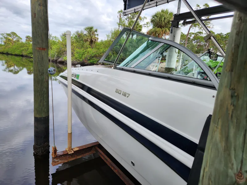 Slide: The Image of 2019 Hurricane SunDeck 187 OB boat docked by a serene riverbank. - 5