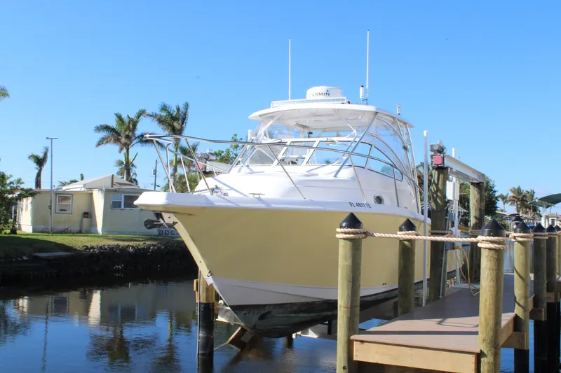 Slide: The Image of 2006 Pro-Line 32 Express boat docked by palm trees and waterfront homes. - 2