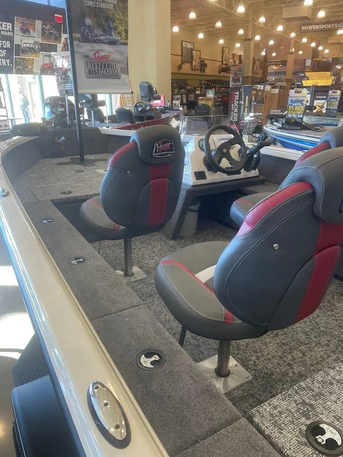 Slide: The Image of 2025 Ranger VS1665SC boat interior with gray and red seating, steering console, and carpeted flooring. - 2