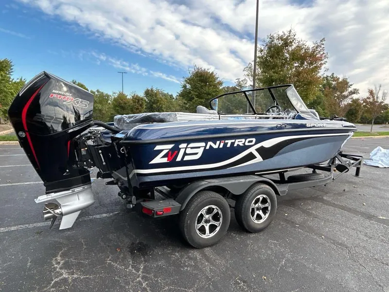 Slide: The Image of 2025 Nitro ZV19 Sport boat on trailer, parked outdoors, with trees in the background. - 2
