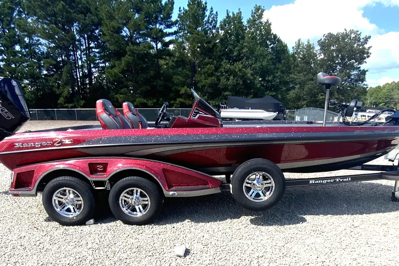 The Image of 2025 Ranger Z521R boat with dual-axle trailer, parked on gravel, surrounded by trees. - 0