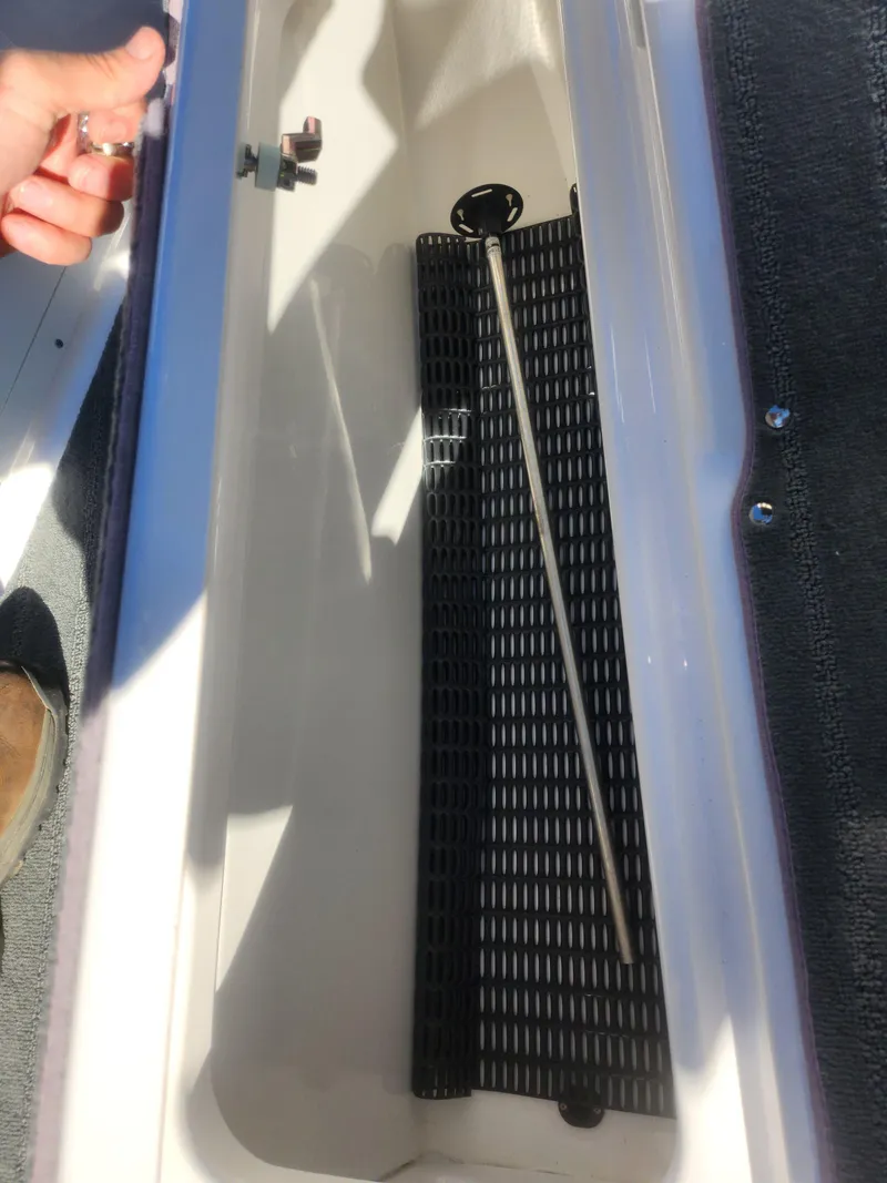 Slide: The Image of 2023 Yamaha AR190 boat storage compartment with black mat and metal rod. - 13