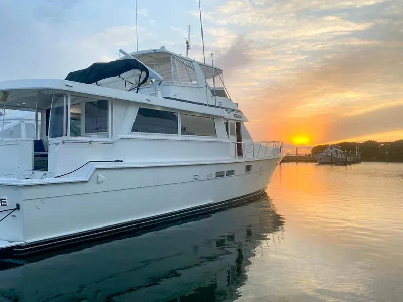 Slide: The Image of 1990 Hatteras 62 Cockpit Motor Yacht at sunset on calm water. - 2