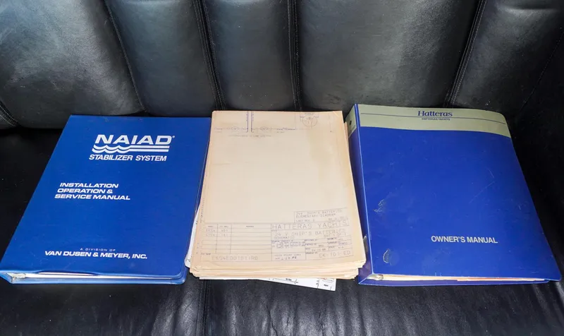 Slide: The Image of Manuals for 1990 Hatteras 62 Cockpit Motor Yacht and Naiad Stabilizer System on a leather seat. - 21