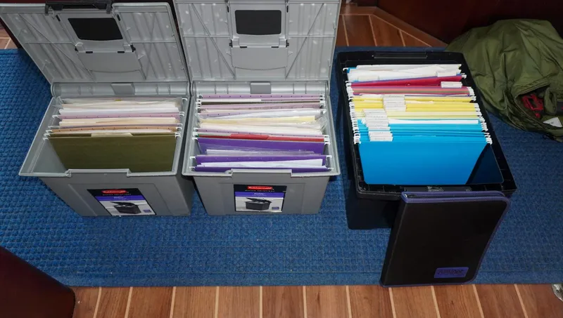 Slide: The Image of Organized file boxes with colorful folders on a yacht's wooden floor. - 23