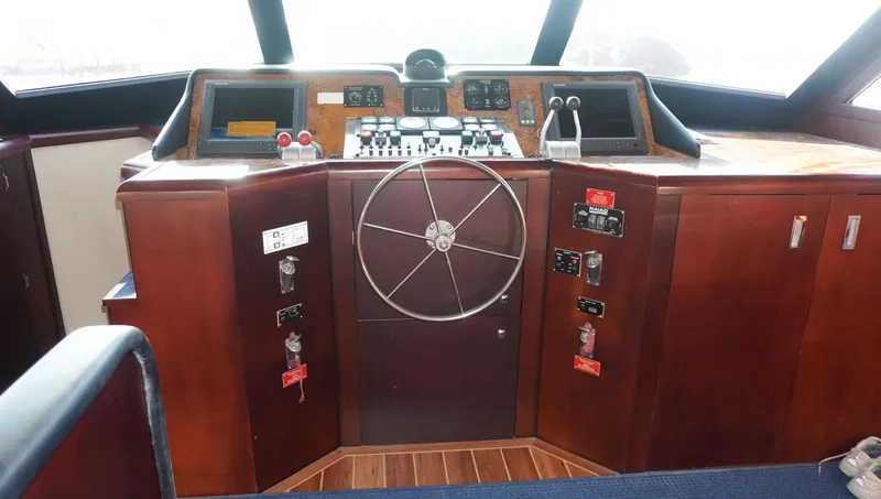 Slide: The Image of 1990 Hatteras 62 Cockpit Motor Yacht helm with wooden dashboard and steering wheel. - 24