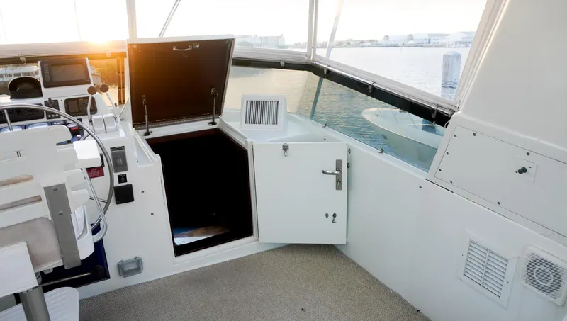 Slide: The Image of 1990 Hatteras 62 Cockpit Motor Yacht helm with open hatch, overlooking serene waters. - 26