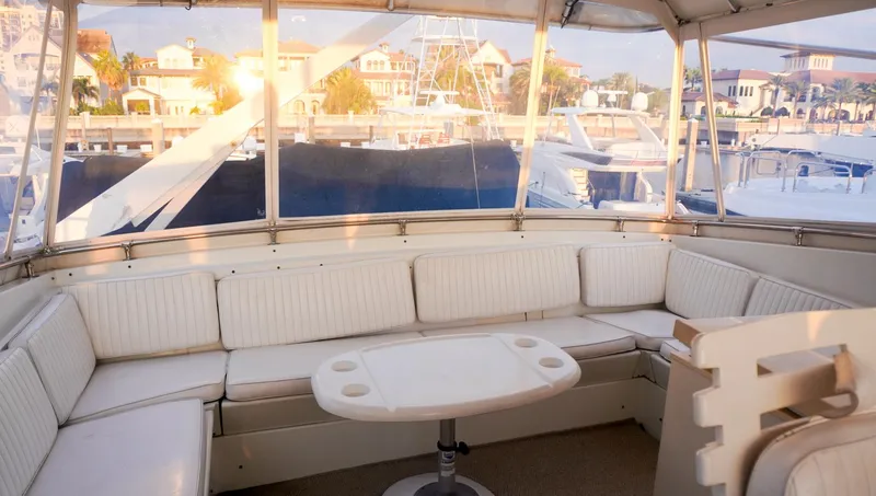 Slide: The Image of Interior of 1990 Hatteras 62 Cockpit Motor Yacht with white seating and marina view. - 31