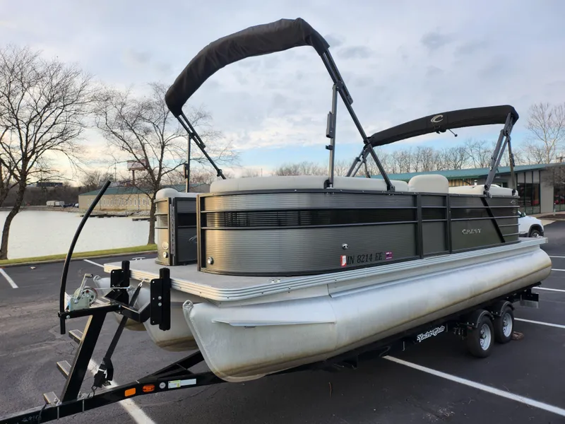 Slide: The Image of 2020 Crest Classic DLX 220 SLC pontoon boat on trailer by a lake. - 8