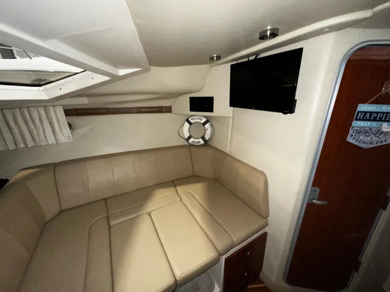 Slide: The Image of 2011 Regal 3060 Window Express cabin with beige seating, TV, and nautical decor. - 30