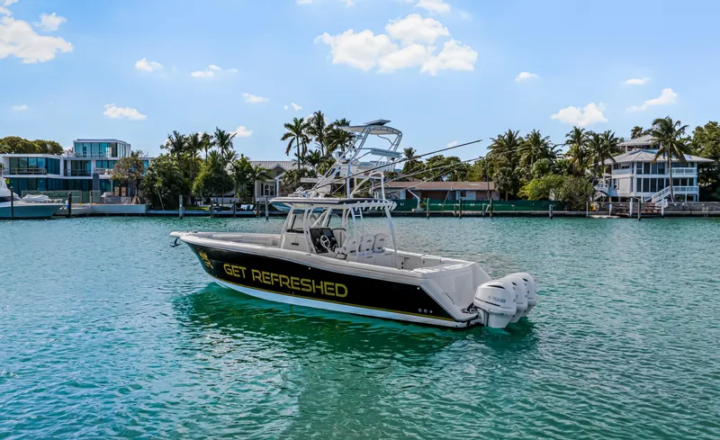 Slide: The Image of 2016 Stamas 390 Tarpon boat on water, surrounded by palm trees and waterfront homes. - 2