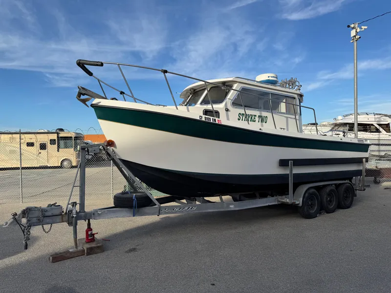 Slide: The Image of 1999 Osprey 26 Legend boat on trailer in a parking lot. - 2