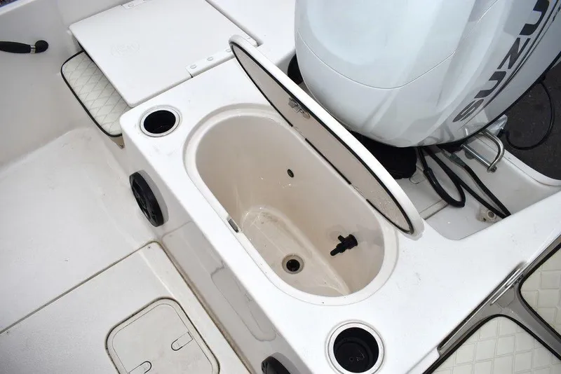 Slide: The Image of 2022 Carolina Skiff 19 LS boat interior with open storage compartment and Suzuki engine. - 18