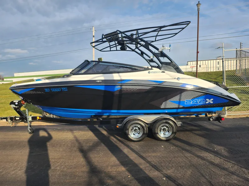 Slide: The Image of 2016 Yamaha Boats 242X E-Series on trailer, black and blue design, parked outdoors. - 4