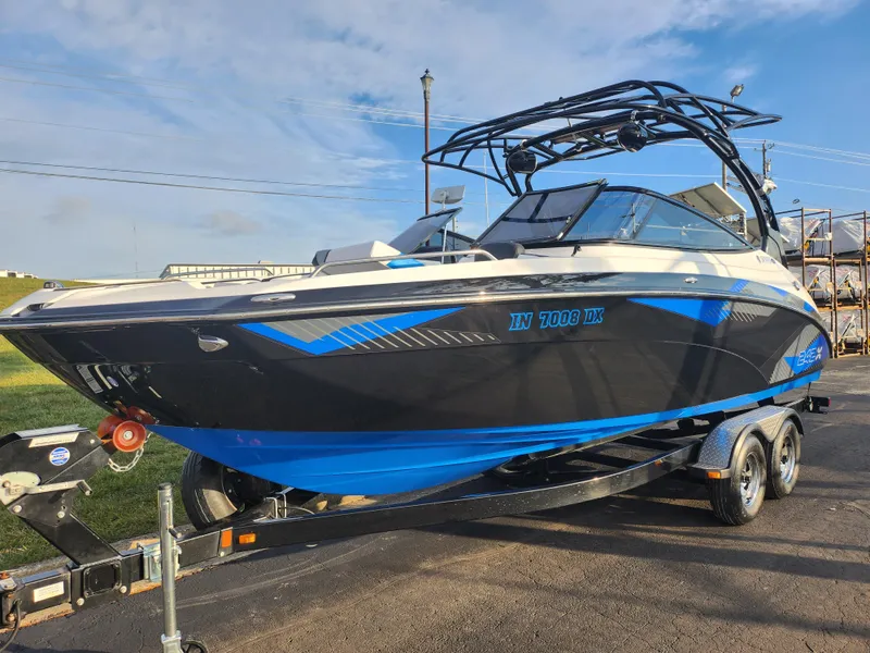 Slide: The Image of 2016 Yamaha Boats 242X E-Series on trailer, black and blue design, parked outdoors. - 5