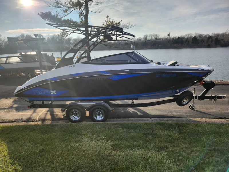 Slide: The Image of 2016 Yamaha Boats 242X E-Series on trailer by a lake. - 9