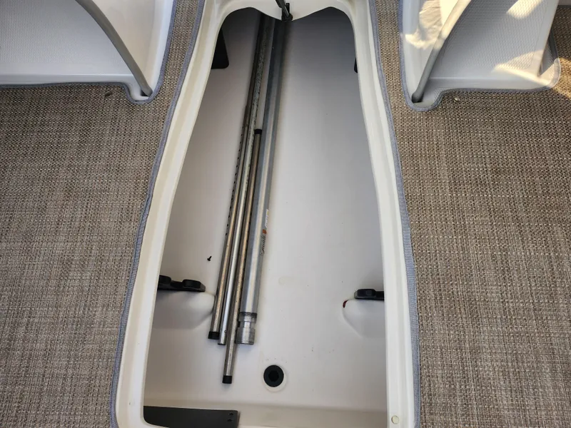 Slide: The Image of 2013 Nitro 290 Sport boat storage compartment with metal rods on carpeted floor. - 13