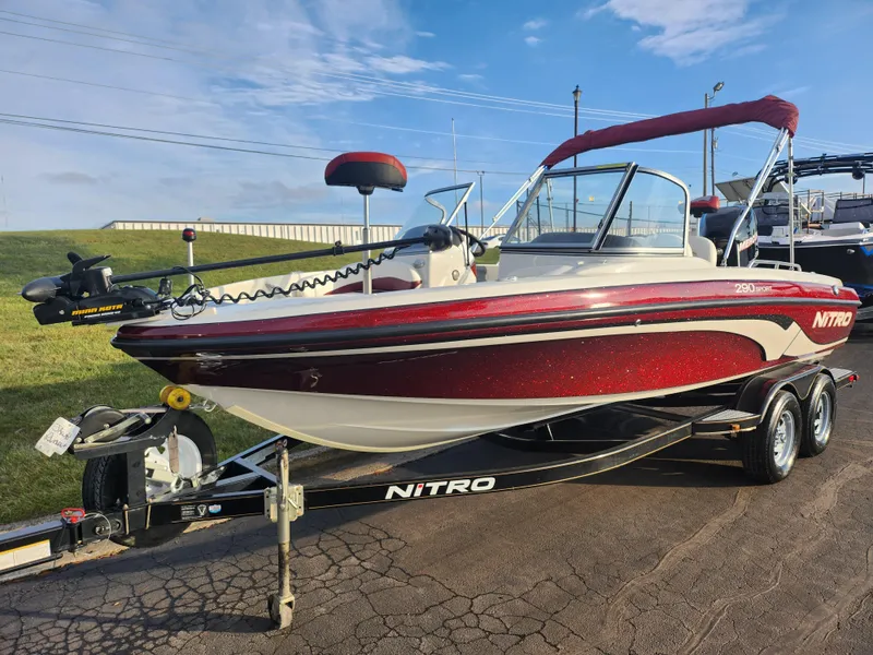 Slide: The Image of 2013 Nitro 290 Sport boat on trailer, red and white design, parked outdoors. - 5