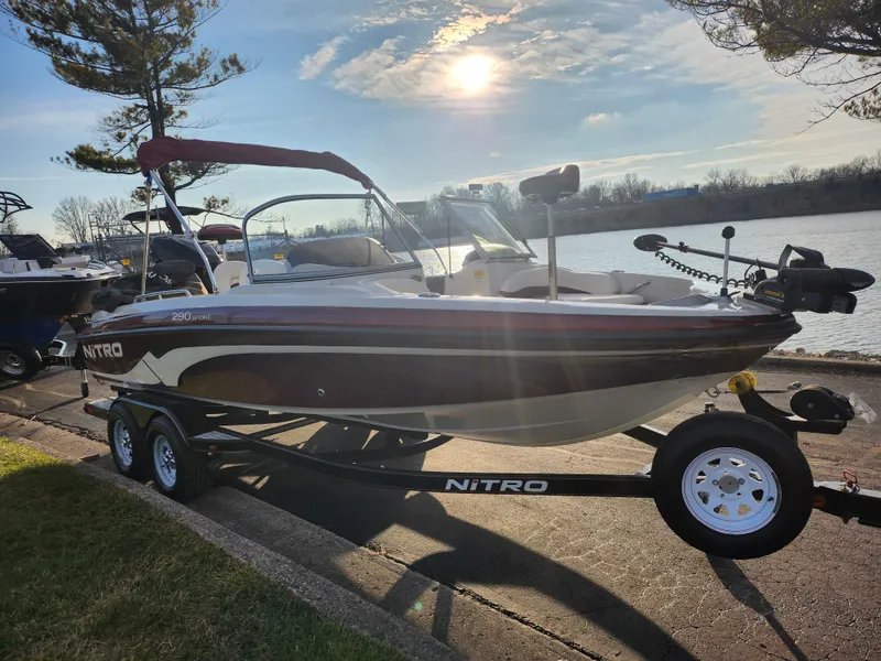 Slide: The Image of 2013 Nitro 290 Sport boat on trailer by a lake under a sunny sky. - 9