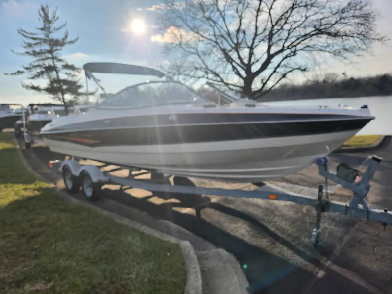 Slide: The Image of 2007 Bayliner 225 boat on trailer, parked near a lake under a sunny sky. - 8