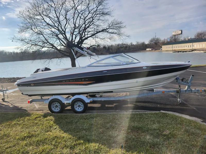 Slide: The Image of 2007 Bayliner 225 boat on trailer by a lake, clear sky, and tree in background. - 9
