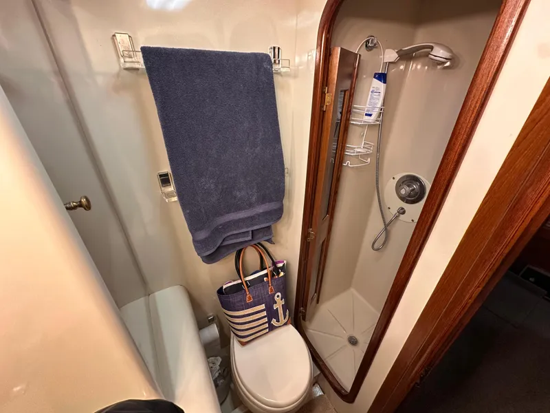 Slide: The Image of 1989 Viking 44 Motor Yacht bathroom with shower, toilet, towel, and nautical-themed bag. - 32