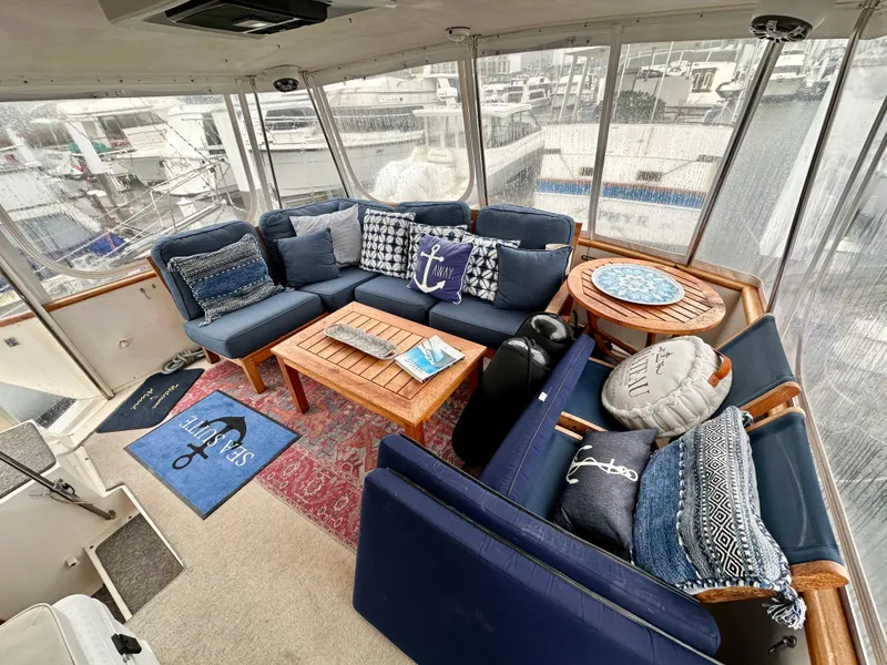Slide: The Image of 1989 Viking 44 Motor Yacht interior with blue seating, nautical decor, and marina view. - 7