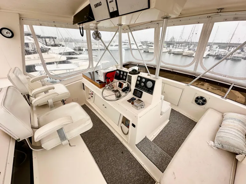 Slide: The Image of 1989 Viking 44 Motor Yacht helm with white seating, steering wheel, and marina view. - 9