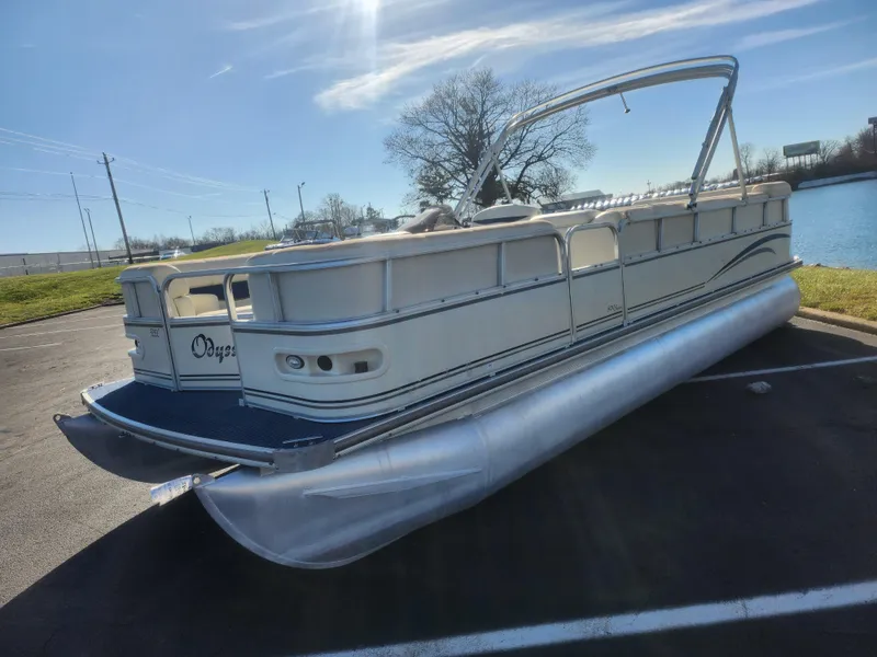Slide: The Image of 2005 Odyssey 522C pontoon boat parked near a lake under a clear blue sky. - 5