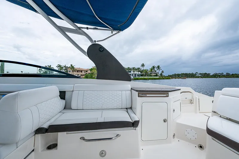 Slide: The Image of 2018 Sea Ray SDX 290 Outboard interior with white seating and blue canopy. - 16