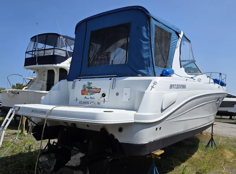 Slide: The Image of 2003 Four Winns 328 Vista boat with blue canopy, parked on land. - 38