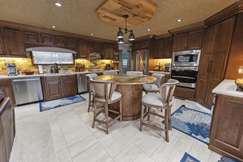 Slide: The Image of Spacious kitchen with wooden cabinets, island seating, stainless steel appliances, and modern lighting. - 13