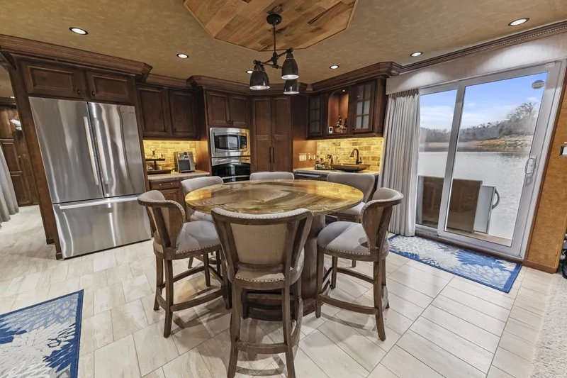 Slide: The Image of Spacious kitchen with wooden cabinets, round dining table, and modern appliances, overlooking a scenic view. - 14