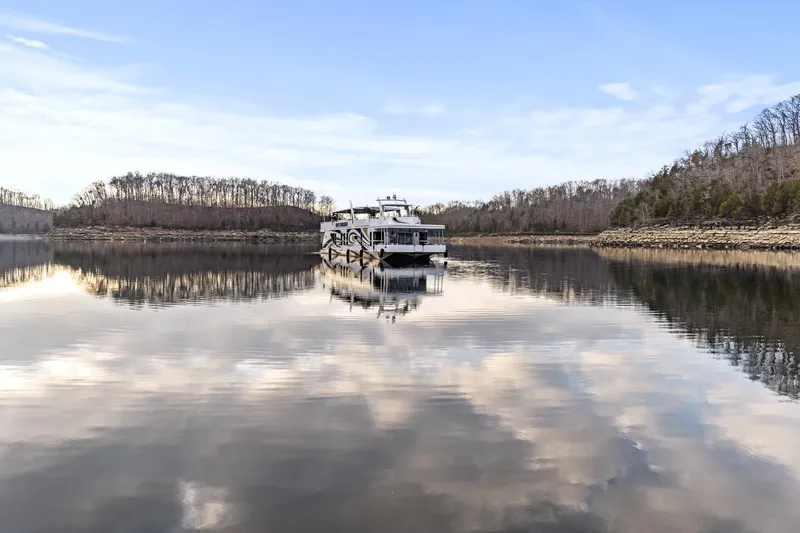 Slide: The Image of Houseboat on calm lake with cloudy sky reflection, surrounded by bare trees. - 46