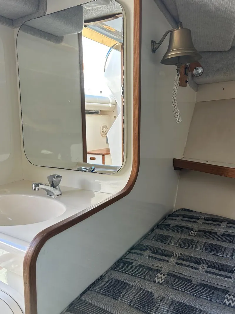 Slide: The Image of 1988 Bertram 28 Moppie cabin interior with sink, mirror, and nautical bell. - 5