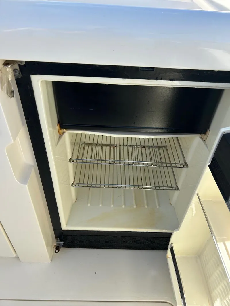 Slide: The Image of Open refrigerator on 1988 Bertram 28 Moppie boat, showing empty shelves. - 9