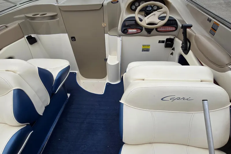 Slide: The Image of 2001 Bayliner 23 Capri boat interior with white and blue seating, steering wheel, and dashboard. - 2