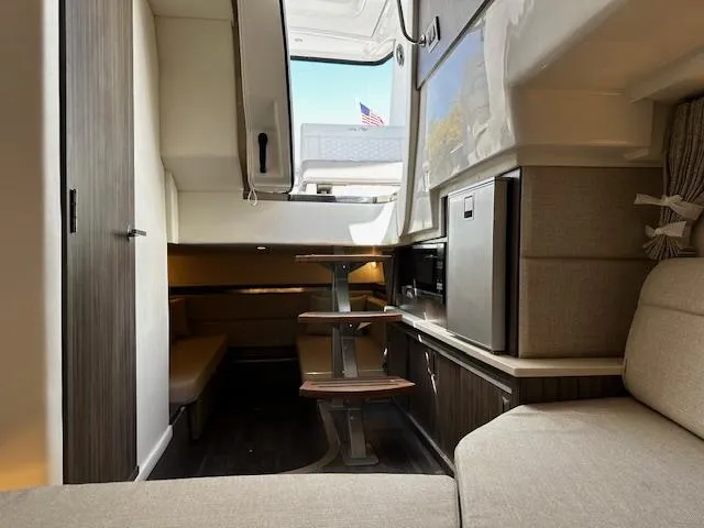 Slide: The Image of Interior of 2024 Sea Ray Sundancer 320 yacht, featuring modern seating and compact kitchenette. - 12
