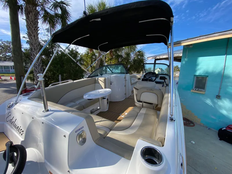 Slide: The Image of 2022 NauticStar 223 DC boat with canopy, spacious seating, and table, docked near a turquoise building. - 14