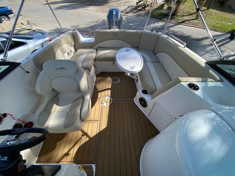 Slide: The Image of 2022 NauticStar 223 DC boat interior with beige seating and wood flooring. - 18