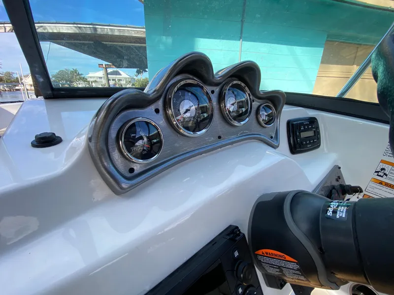 Slide: The Image of 2022 NauticStar 223 DC dashboard with gauges and controls, under a clear blue sky. - 26