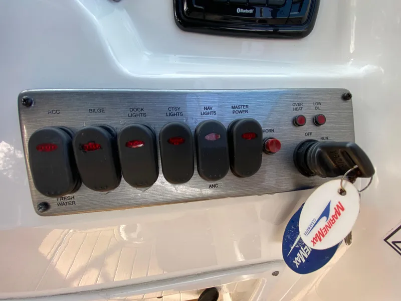 Slide: The Image of Control panel of 2022 NauticStar 223 DC boat with labeled switches and ignition key. - 27