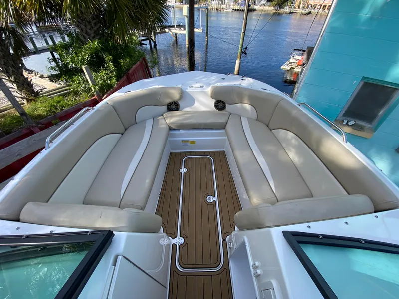 Slide: The Image of 2022 NauticStar 223 DC boat interior with beige seating and wood flooring, docked by the water. - 33
