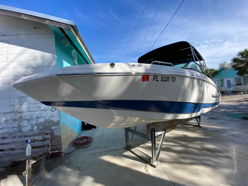 Slide: The Image of 2022 NauticStar 223 DC boat on stand, near turquoise building, sunny day. - 5