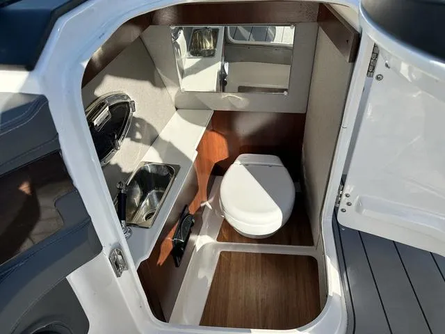 Slide: The Image of 2022 Chaparral 287 SSX boat interior with compact bathroom, sink, and mirror. - 15