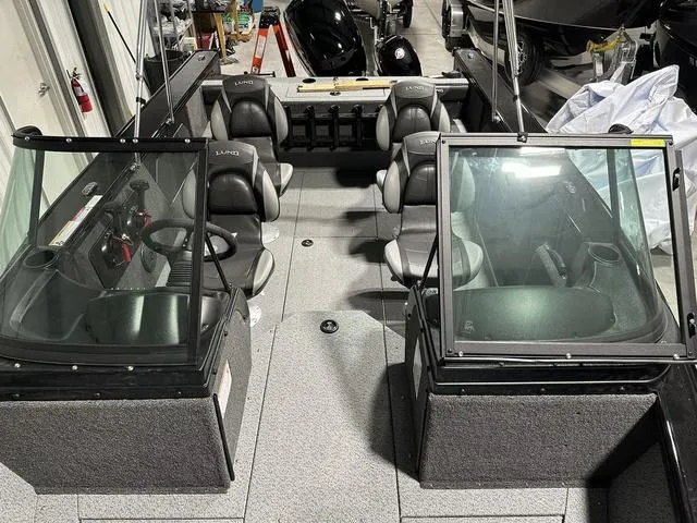Slide: The Image of 2025 Lund 1875 Fisherman Sport boat interior with seating and windshield, in a showroom setting. - 22